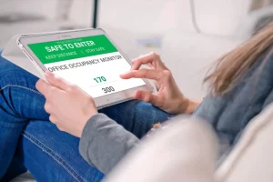 Tablet displaying occupancy monitoring dashboard for COVID-19 safety using WiFi analytics and location services in workplace environment